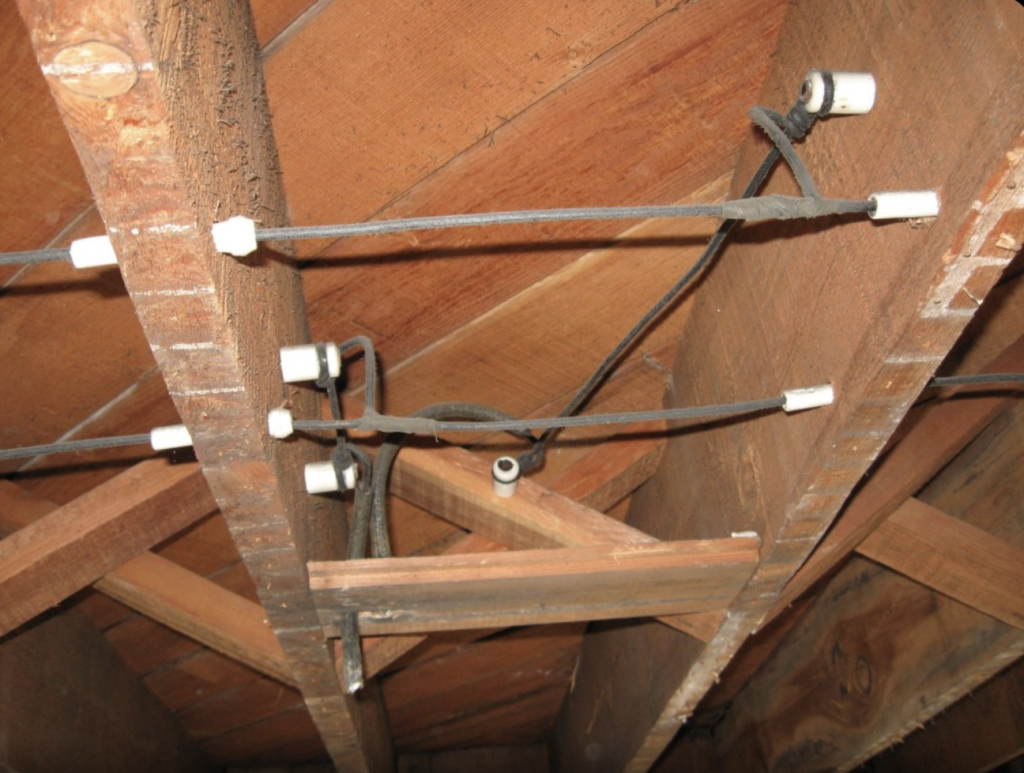 Outdated knob and tube wiring still active inside an older home wall posing a fire risk