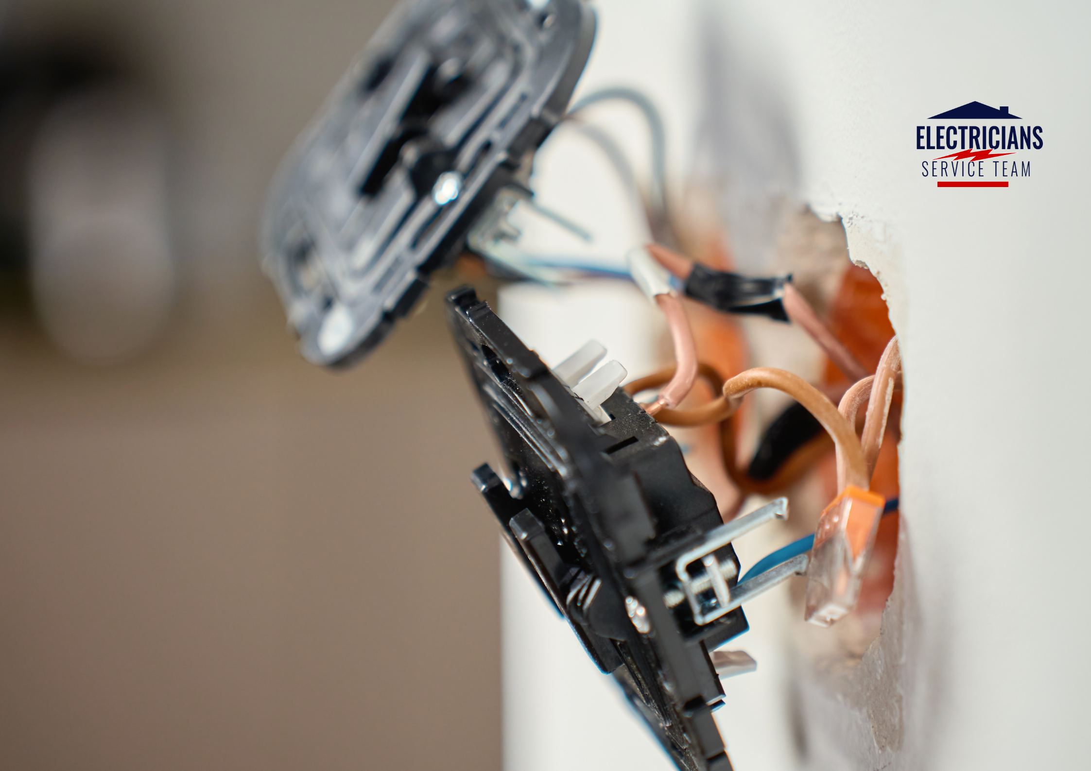 Close-up of a disassembled electrical outlet showing the internal wiring. Several copper wires with tan and blue insulation are connected to the back of a black GFCI receptacle. The image shows the complexity of a professional electrical installation within a wall cavity.