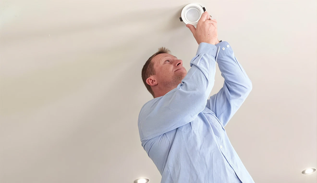 Professional electrician handling recessed lighting installation for a customer